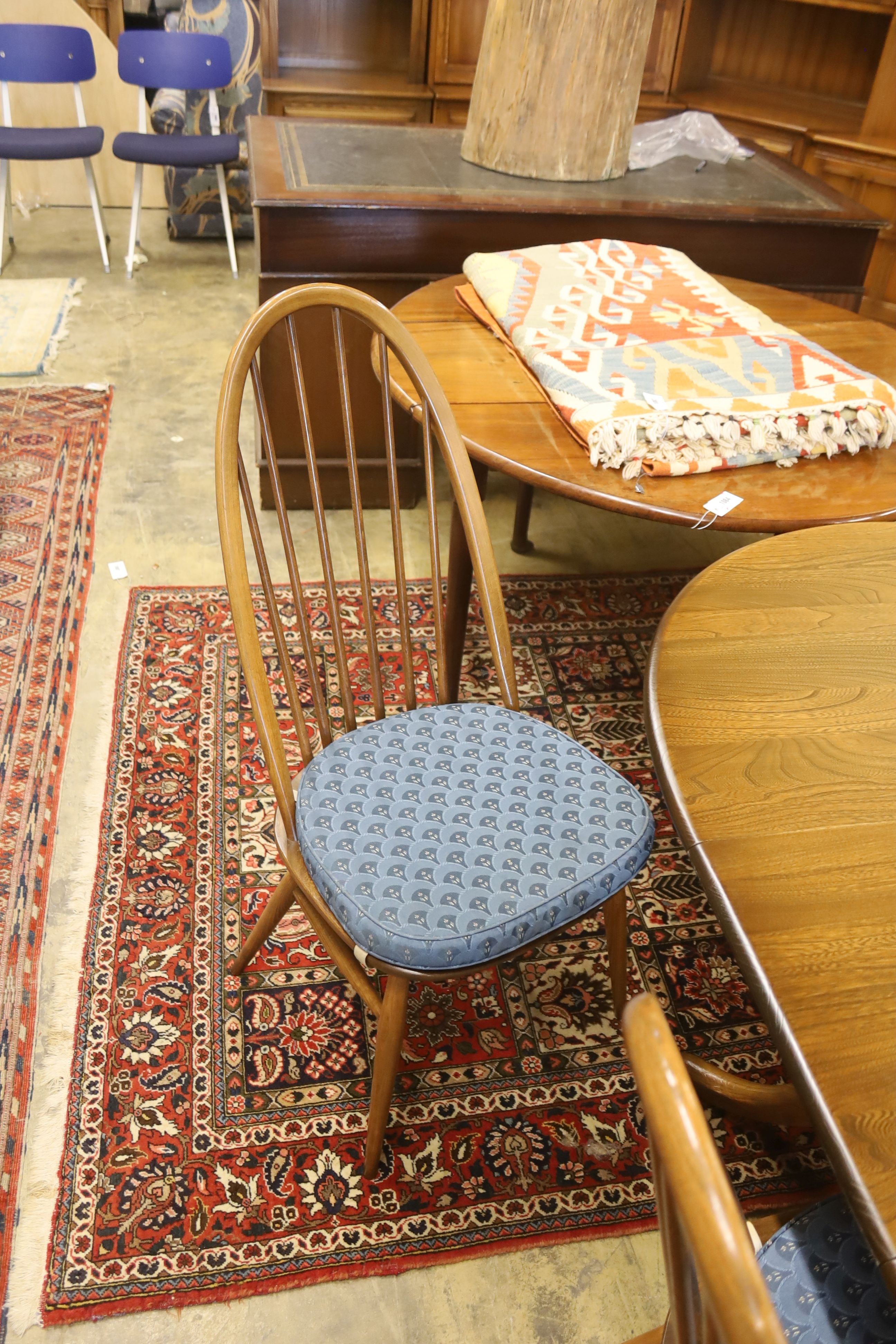 An Ercol elm oval extending dining table, 148cm extended, width 97cm, height 74cm, together with a pair of Ercol elm and beech comb back dining chairs